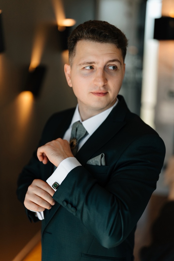 Mihail Tirdea in a dark green suit, adjusting a cufflink.
